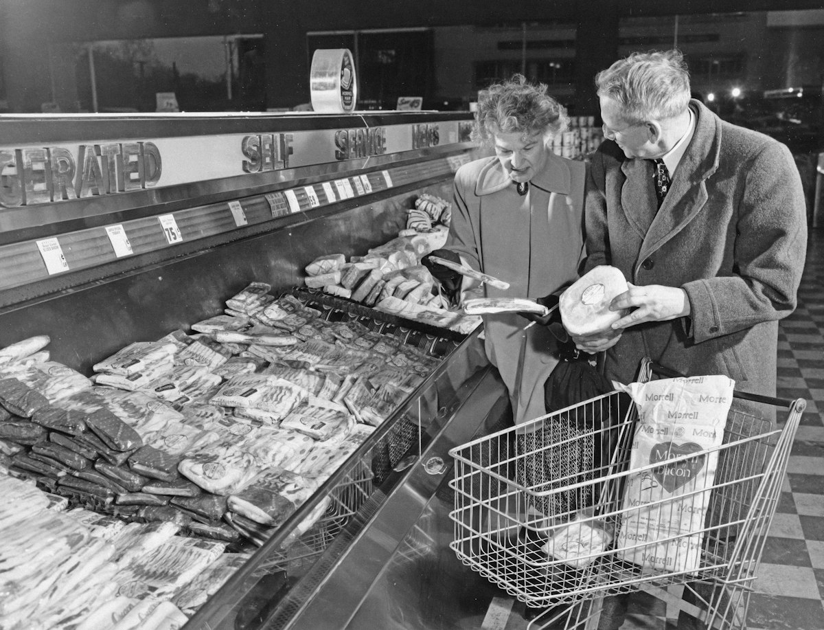 スーパーの売り場で肉を選ぶ買い物客